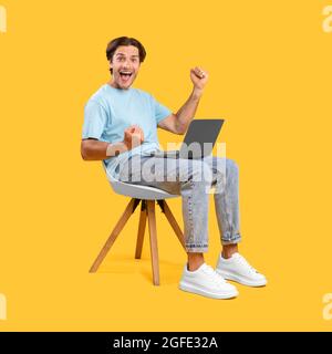 Excited guy using laptop celebrating success shaking fists Stock Photo