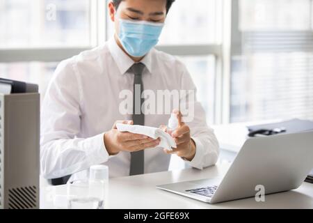 Young businessman using disinfectant in office Stock Photo