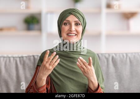 Cheerful Middle-Aged Muslim Woman Talking Making Video Call At Home Stock Photo