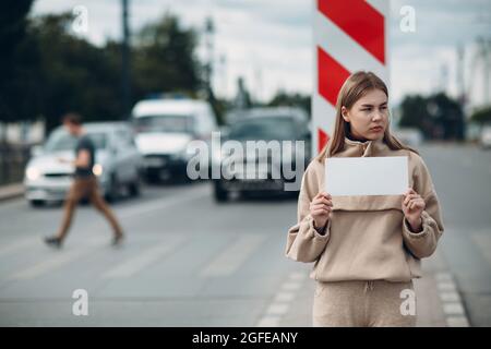 Young woman hold white paper poster in hand. Girl with white blank template sheet in hands Stock Photo