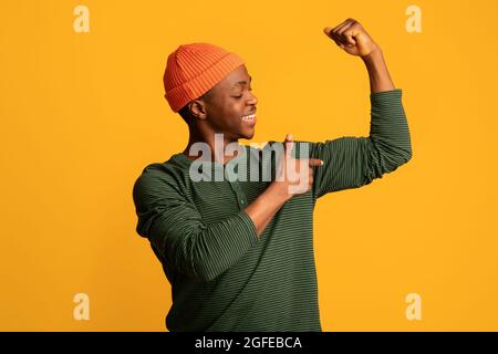 Happy Young African American Guy Pointing At His Biceps While Pumping Fist Stock Photo