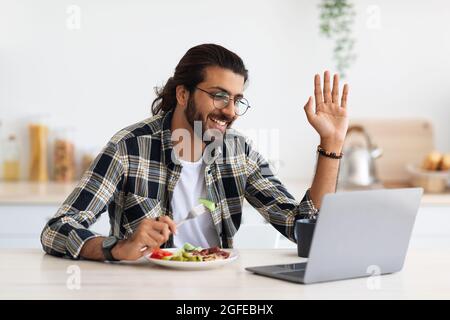 Positive middle-eastern man having video call during breakfast at home Stock Photo