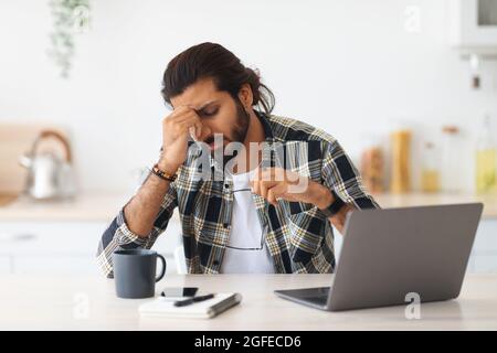 Tired middle-eastern man freelancer having difficulties at job Stock Photo