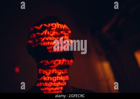 Young man with red letters on his face in the dark Stock Photo