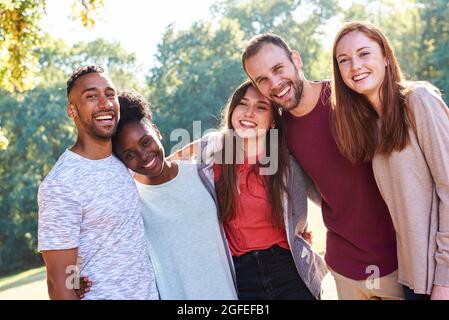 Portrait of smiling young friends standing in park Stock Photo
