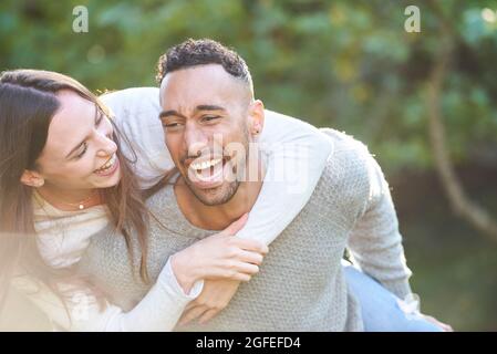 Smiling young man giving piggyback ride to his partner Stock Photo