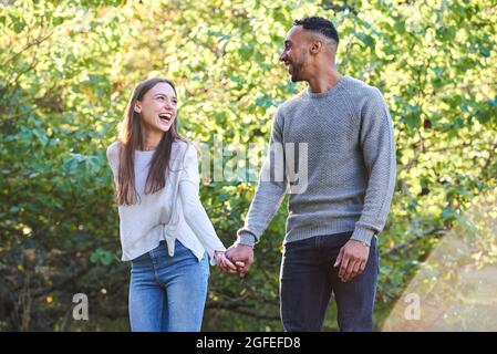 Smiling young couple looking at each other in public park Stock Photo