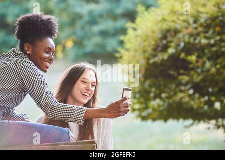 Smiling young friends talking selfie on smartphone Stock Photo