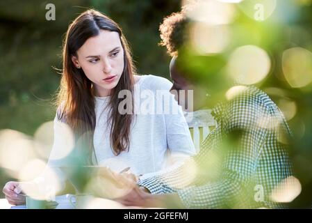 Young female friends using digital tablet while studying in park Stock Photo