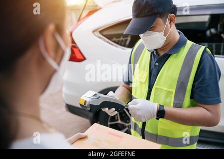Asian delivery man using a credit card reader while delivering products to customers at home, delivery destination. Stock Photo