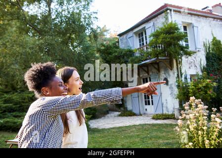 Young woman pointing at something in distance to her friend Stock Photo