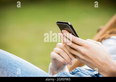 Mid section of young woman using smartphone in park Stock Photo