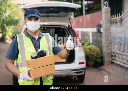 A delivery man thumbs up and wearing masks to prevent the spread of coronavirus or COVID-19 Stock Photo