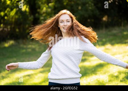 Portrait of smiling young woman turning around in park Stock Photo