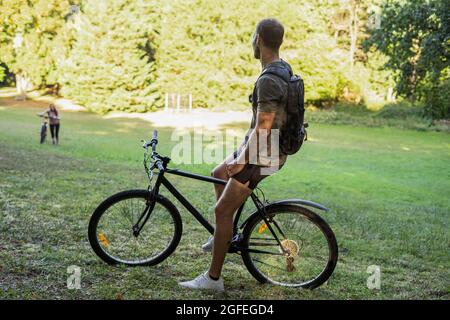 Young man sitting on bicycle while relaxing in forest Stock Photo