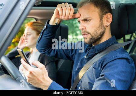 Frustrated young man using smart phone while driving a car Stock Photo