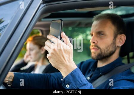 Young man using smart phone while driving a car Stock Photo