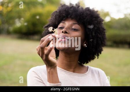 Young woman blowing dandelion flower Stock Photo