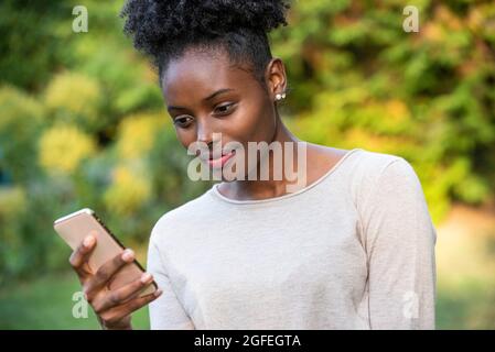 Close-up of smiling young woman using smartphone in park Stock Photo