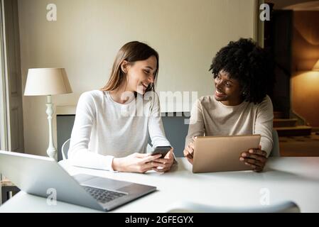 Smiling young women using digital tablet and smart phone at home Stock Photo
