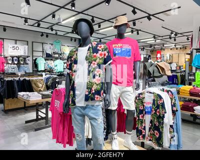 Moscow, Russia, June 2021: Men's Clothing Department. Two male mannequins in T-shirts, shorts, a Hawaiian shirt. Shelves with casual-style clothes are Stock Photo