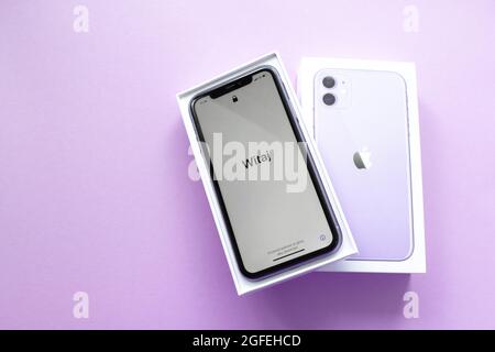 Moscow, Russia, May 2021: A new iPhone 12 model of violet color in an open branded box on a lilac background. On the iPhone screen, a welcome in Polis Stock Photo