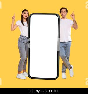 Couple standing next to big white empty smartphone screen Stock Photo