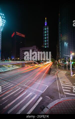 Traffic moving on city street with Taipei 101 building in background, Taiwan Stock Photo