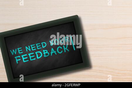 We need your feedback hand Written in Small chalkboard on Wooden background with Copy space. Blue Chalk. Customer feedback Concept Stock Photo