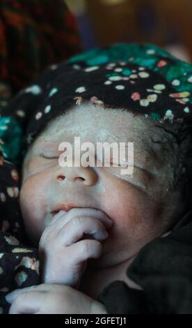 Beautiful baby boy a few seconds after the birth. Baby after birth. Stock Photo