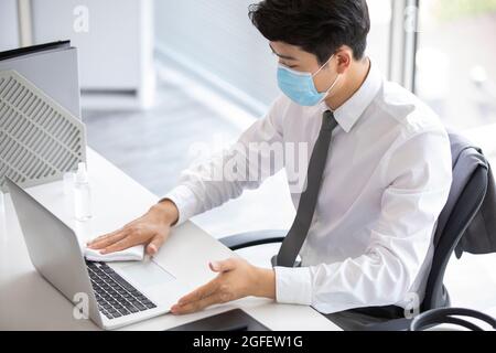 Young businessman using disinfectant in office Stock Photo