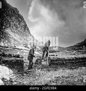 An early 20th Century photograph of locals digging out turf (aka peat) in the Gap of Dunloe, a narrow mountain pass that separates the MacGillycuddy's Reeks mountain range in the west, from the Purple Mountain Group range in the east in the  Killarney National Park in County Kerry, Ireland Stock Photo