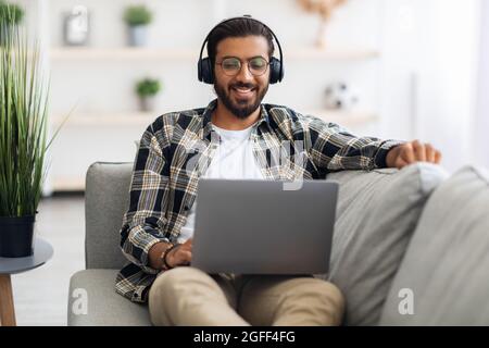 Relaxed middle-eastern guy watching movie online, using laptop Stock Photo