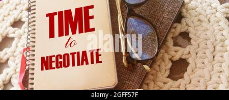 Business concept. Notebook with text TIME TO NEGOTIATE sheet of white paper for notes, glasses and pen Stock Photo
