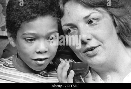 Austin Texas USA, circa 1984: Mother and adopted child listen to Space Shuttle conversations on telephone. ©Bob Daemmrich Stock Photo