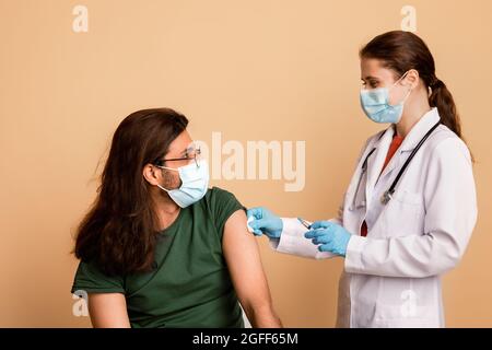 Female doctor making vaccination for long-haired indian guy Stock Photo