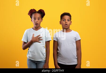 Amazed afro american brother and sister on yellow Stock Photo