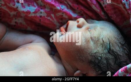 Beautiful baby boy a few seconds after the birth. Baby after birth. Stock Photo