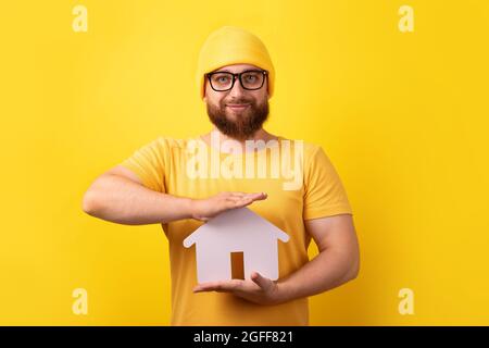 the realtor holding the house over yellow background, the concept of buying, selling or renting a home Stock Photo