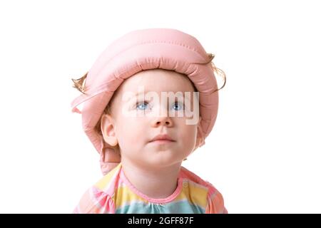 caucasian little girl wearing a pink  helmet looking up, baby isolated over white background Stock Photo