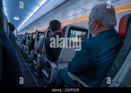 Istanbul, Turkey - 03.08.2021: old man with white hair and protective mask look at corridor of airplane before takeoff time while sitting on his seat Stock Photo