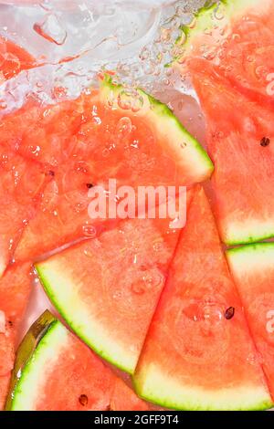 Close-up fresh slices of red melon on white background. Slices of melon in sparkling water on white background, close-up. Copy space Stock Photo