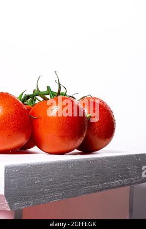 A vertical shot of three red tomatoes sitting on a tray against a dark  background Stock Photo - Alamy