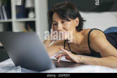 Woman on bed with laptop Stock Photo