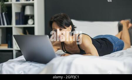 Woman lying with laptop on bed Stock Photo