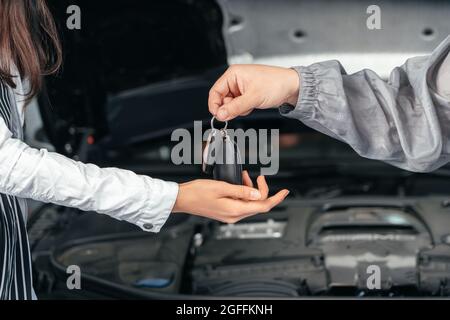 Man giving client keys to her repaired car in auto repair service Stock Photo