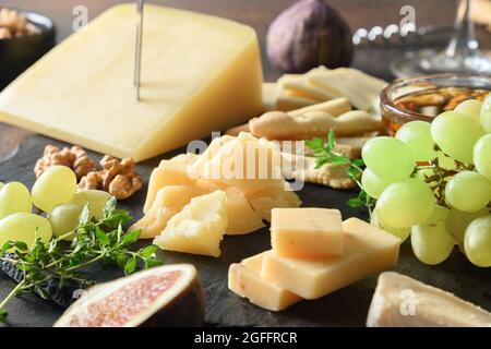 Cheese platter with grapes, nuts, figs on black slate plate. Close up. Festive appetizer. Party food. Stock Photo