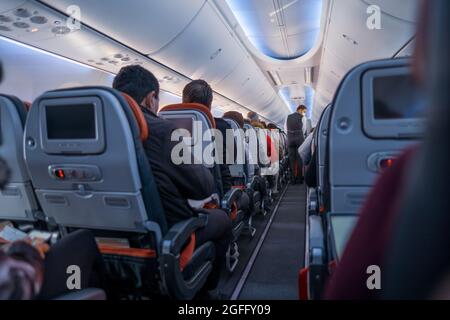 Arnavutkoy, Istanbul, Turkey - 03.08.2021: steward with protective mask service on air travel and passengers wait on seats in Turkish Airlines flight Stock Photo