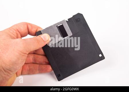Old computer and data storage technology, hand heldblack plastic magnetic floppy disk 3½ inches, isolated on white background Stock Photo