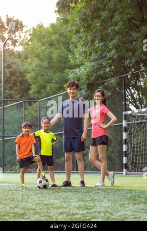 Happy young family playing football on soccer field Stock Photo